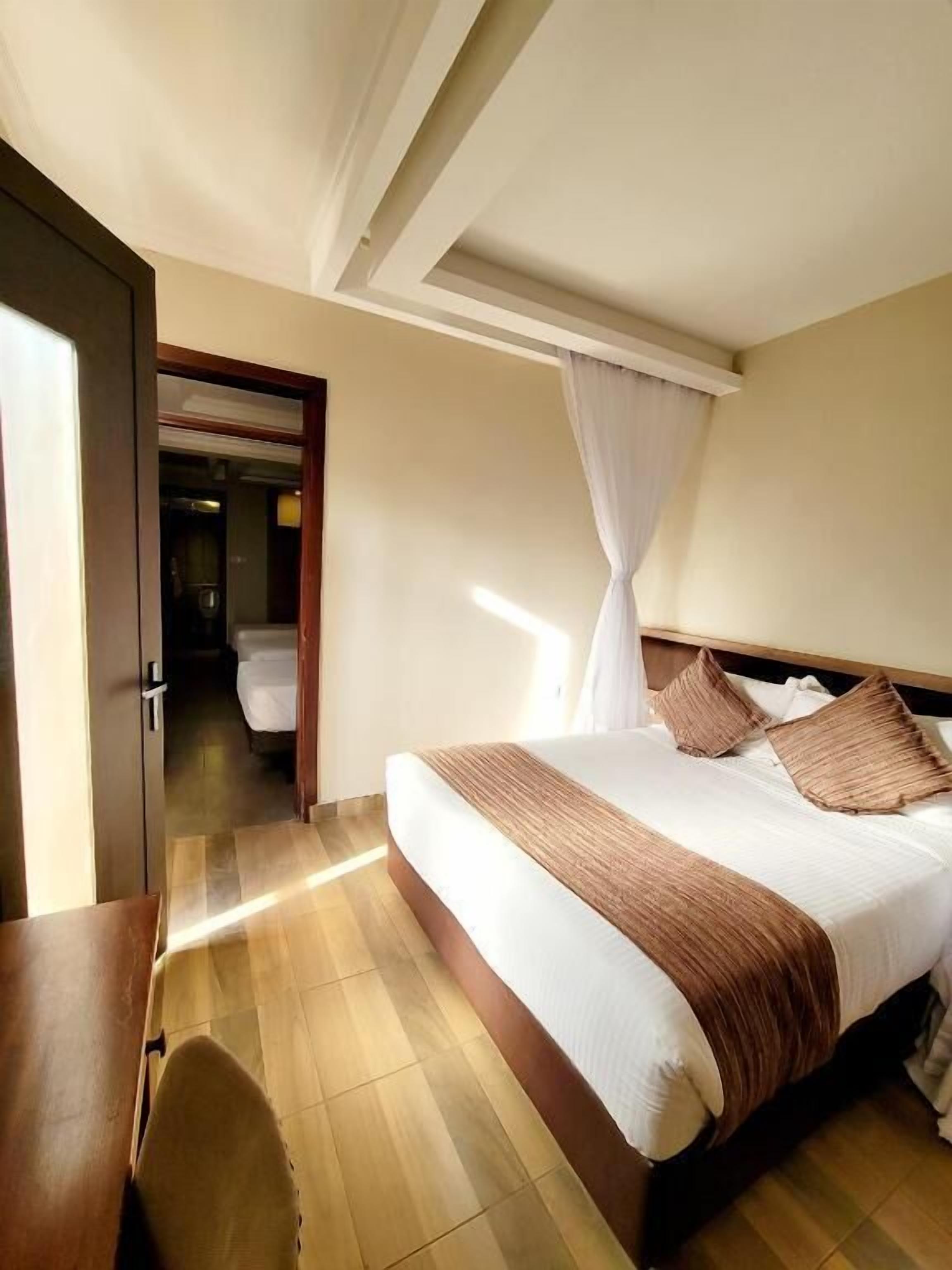 A hotel room with a bed, a desk, and a chair.