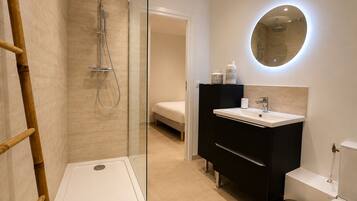 Une salle de bain moderne avec une douche à parois de verre, un lavabo blanc et des toilettes.