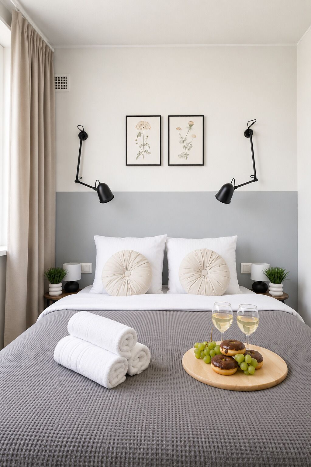 A neatly made bed with white linens, two wall-mounted lamps, and a framed botanical print above it.