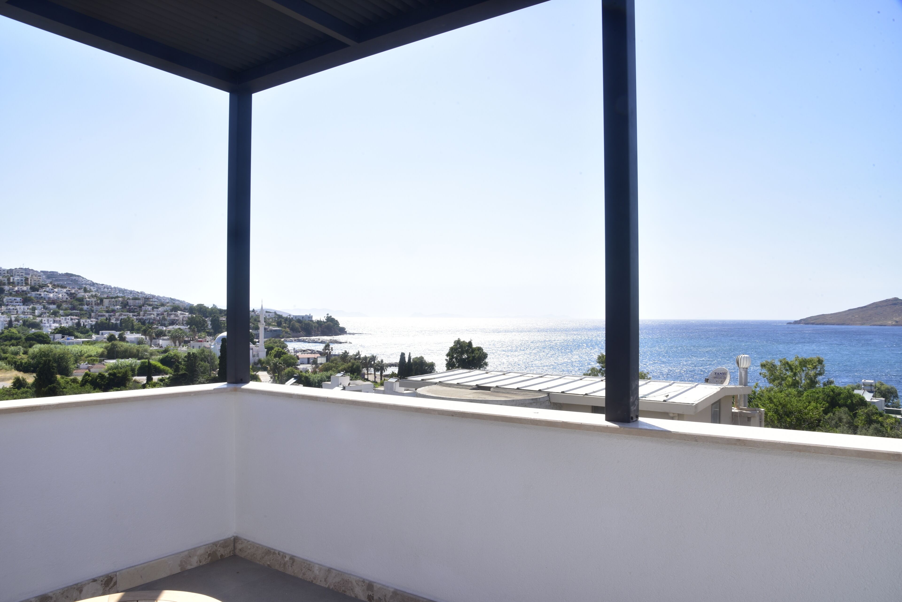 Un balcón con vista al mar y un pueblo lejano.