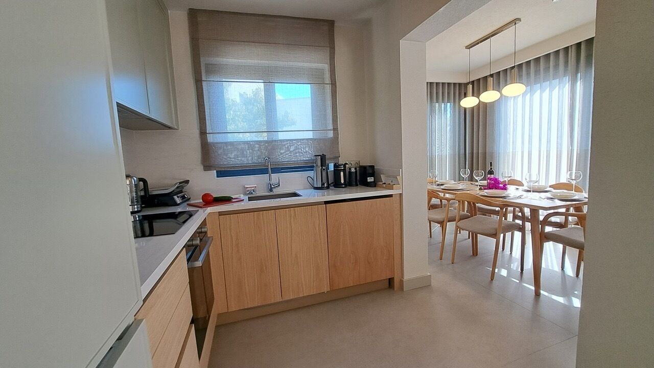 Una cocina moderna con una isla central, armarios de madera y un comedor con mesa y sillas.