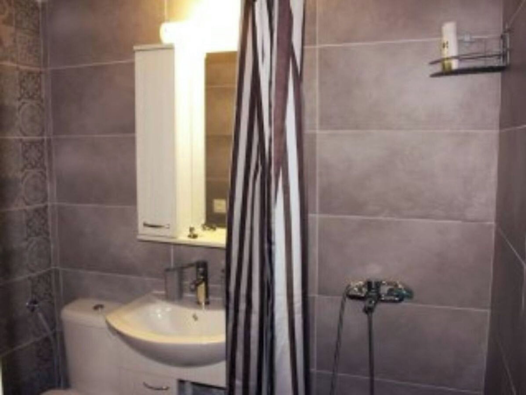 A bathroom with a sink, mirror, and shower curtain.