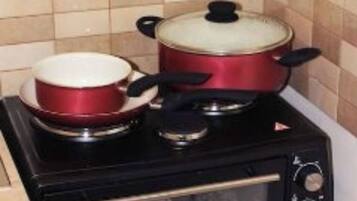 Une cuisine avec un fourneau noir, deux casseroles et un four à micro-ondes.