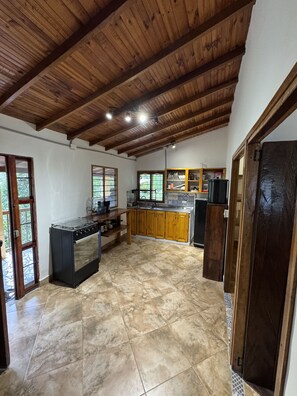 Uma cozinha espaçosa com uma grande ilha, vigas de madeira no teto e piso ladrilhado.