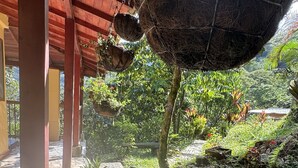 Un espace extérieur abrité, agrémenté de jardinières suspendues, de murs en pierre et d’un sol carrelé.