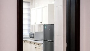 Eine Küche mit weißen Schränken, einem Edelstahl-Kühlschrank und einer Mikrowelle.