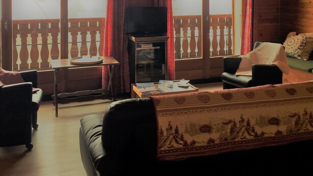 A cozy cabin interior with a wooden ceiling, a sofa, a television, and a dining table. - 100 M² DUPLEX "SPECIAL OFFER" IN THE HEART OF LES CARROZ—Sleeps 9, 3 bedrooms, 2 bathrooms (Arâche -La-Frasse)