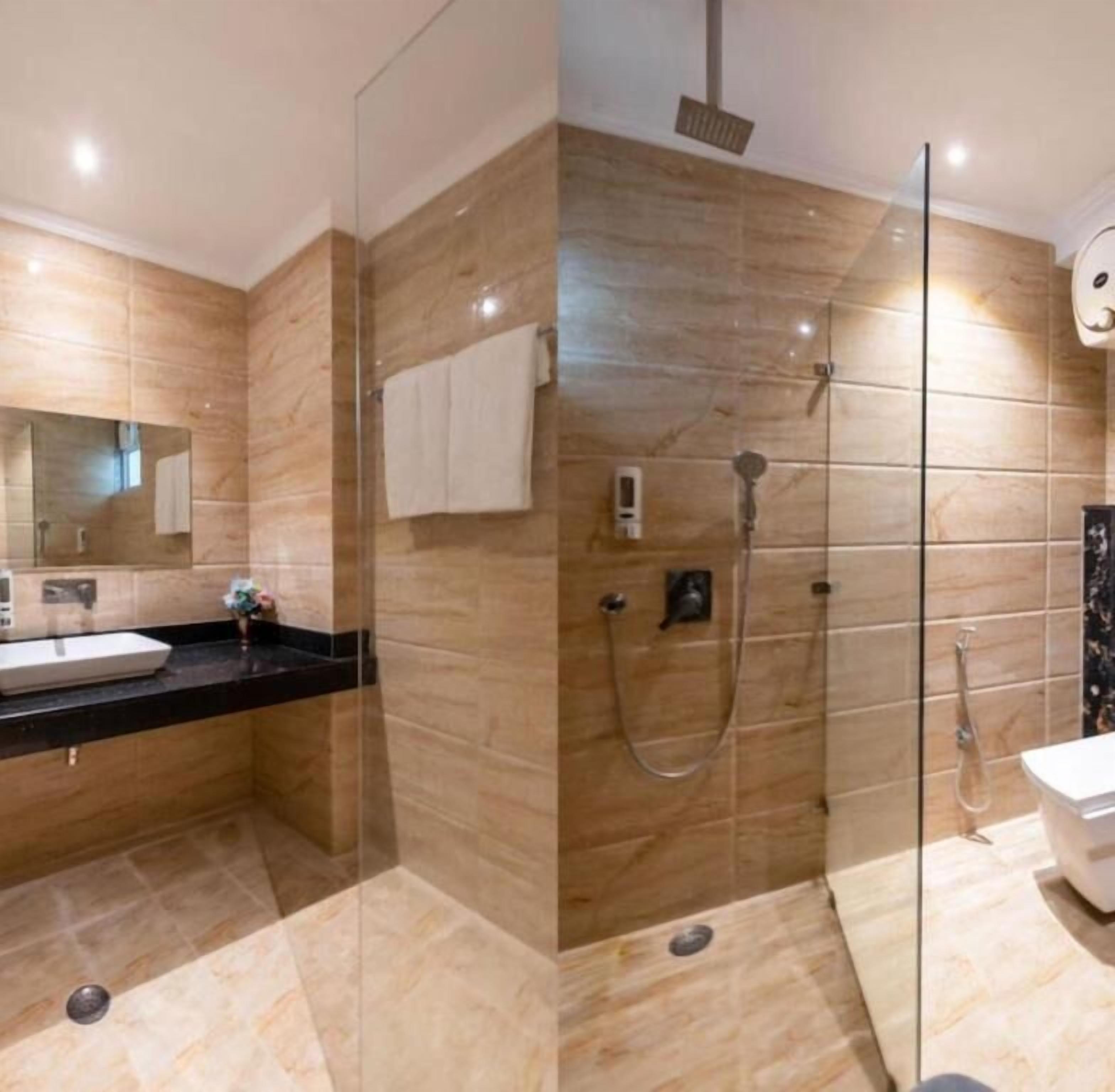A modern bathroom with a glass shower enclosure, a sink with a black countertop, and a white toilet.