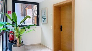 A hallway with a potted plant, a door, a window, and a fire extinguisher. - Beautiful apartment for 7 people with WIFI, TV, terrace and pets allowed (Zell Am See)