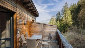 A wooden deck with a table and chairs, overlooking a forested area. - Beautiful apartment for 7 people with WIFI, TV, terrace and pets allowed (Zell Am See)