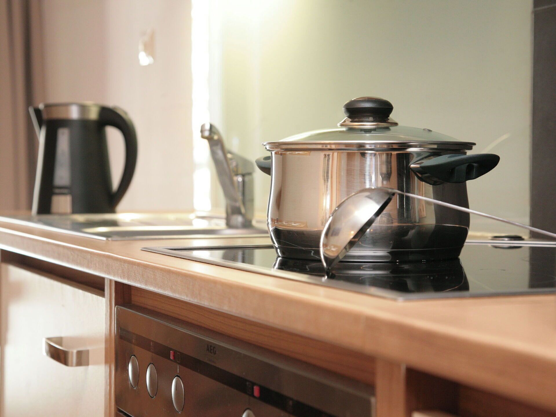 A kitchen with a stove, a pot on the stove, and a coffee maker in the background.