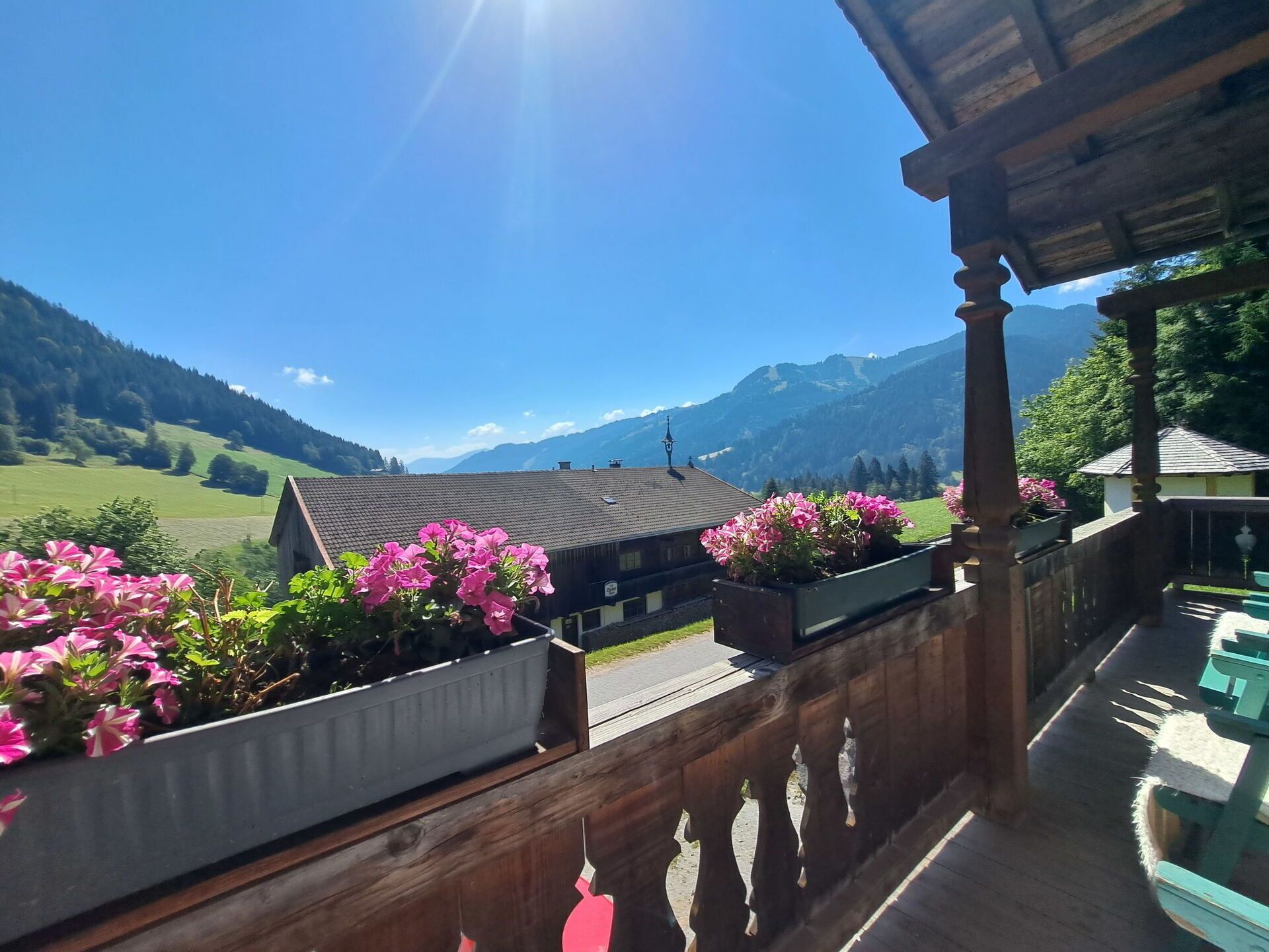 Ein Balkon mit Holzgeländern, Blumentöpfen und Blick auf eine Berglandschaft.
