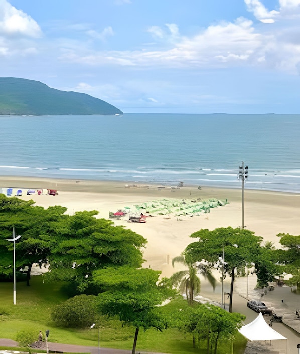 Una playa con vista despejada al océano, orilla arenosa y algo de vegetación.