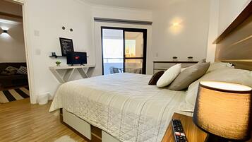 Un dormitorio moderno con cama, mesita de noche, lámpara y escritorio con ordenador.