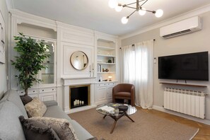 A modern living room with a fireplace, a television, and a comfortable seating area. - A calm, classic two bedroom home in Tetuán, with parquet floors, a decorative fireplace, and a small balcony. Elegant and comfortable for daily life in Madrid. (Madrid)