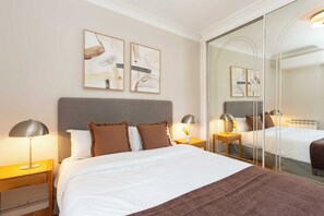 A hotel room with a bed, bedside tables, lamps, and artwork on the wall. - A calm, classic two bedroom home in Tetuán, with parquet floors, a decorative fireplace, and a small balcony. Elegant and comfortable for daily life in Madrid. (Madrid)