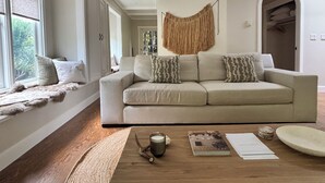 A living room with a sofa, a coffee table, and a view through a window.