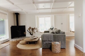 A living room with a fireplace, a sofa, a coffee table, and a large window.