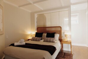 Una habitación de hotel con cama, mesita de noche, lámpara y ventana.