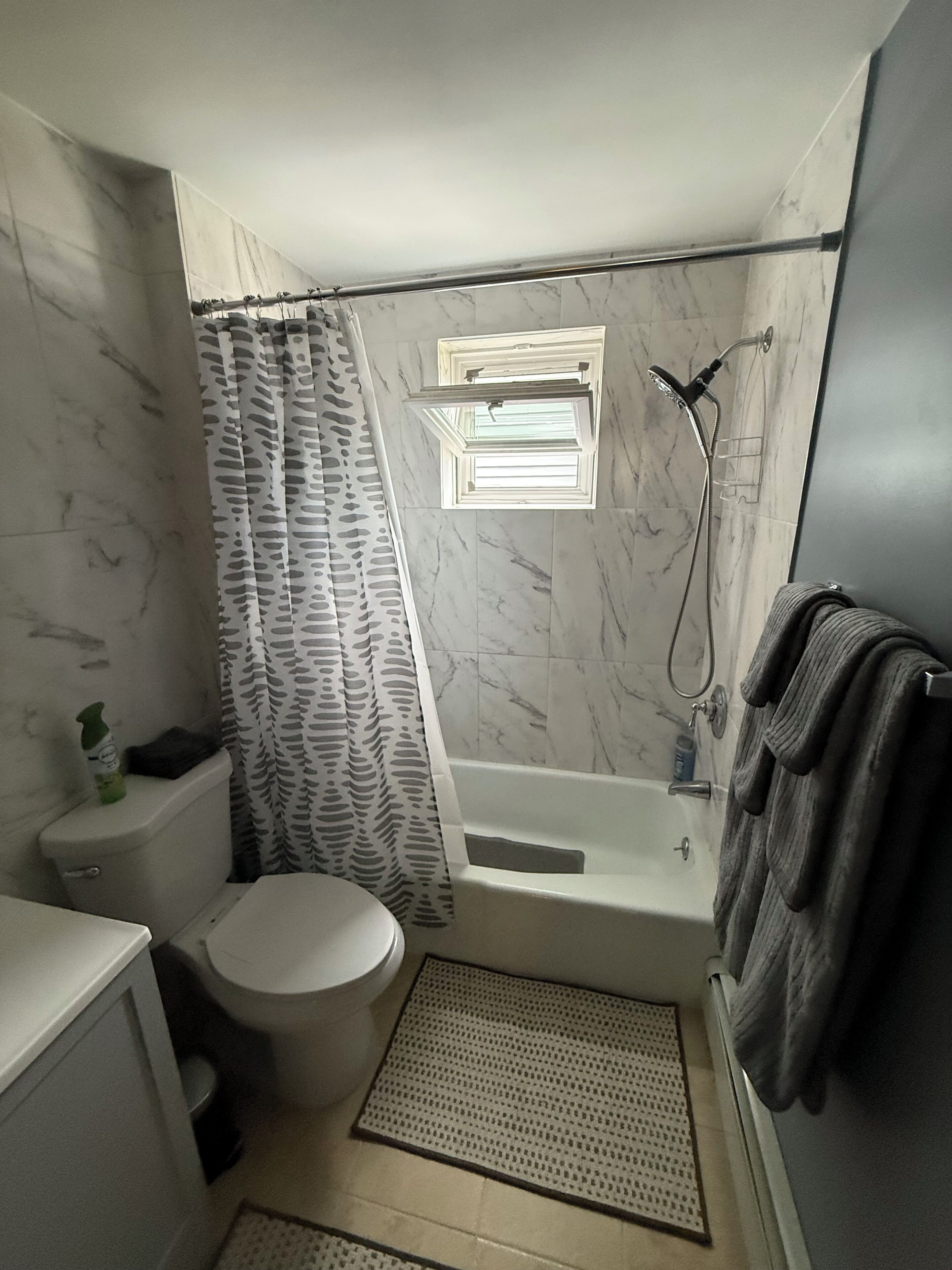 Un baño con inodoro, bañera, ducha y ventana.