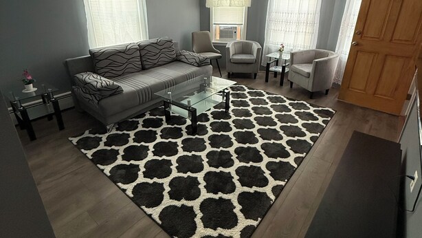 A living room with a grey sofa, two armchairs, a coffee table, and a patterned rug.