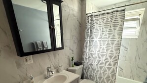 A bathroom with a white sink, mirror, toilet, and bathtub.