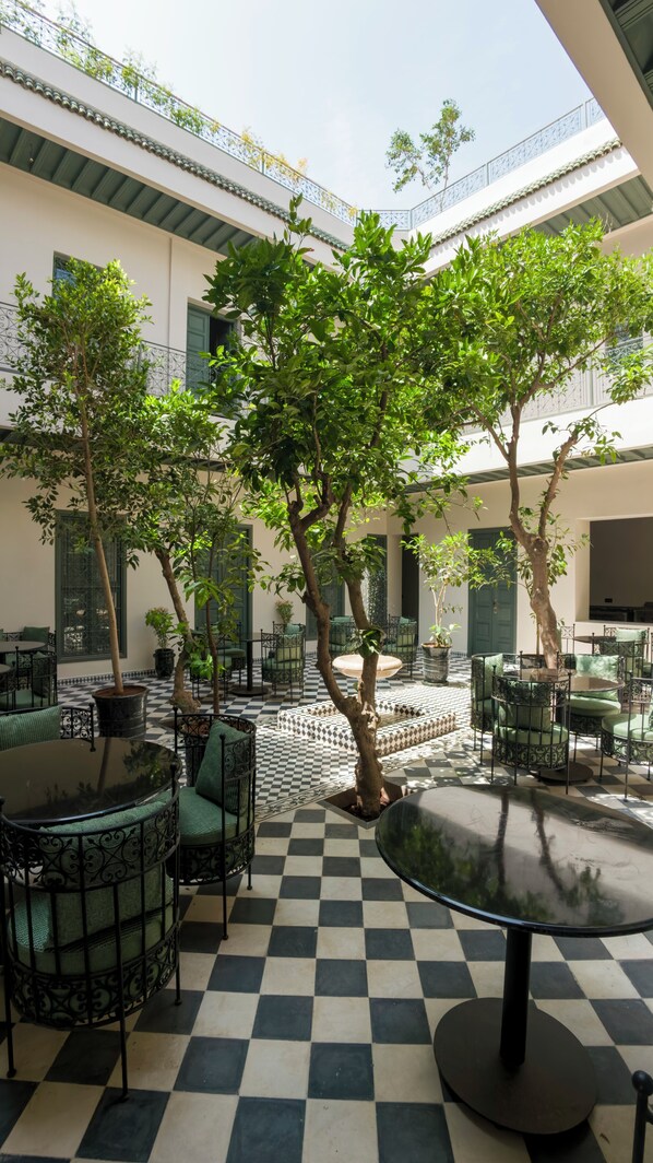 Un patio con piso a cuadros, mobiliario exterior y plantas en macetas.