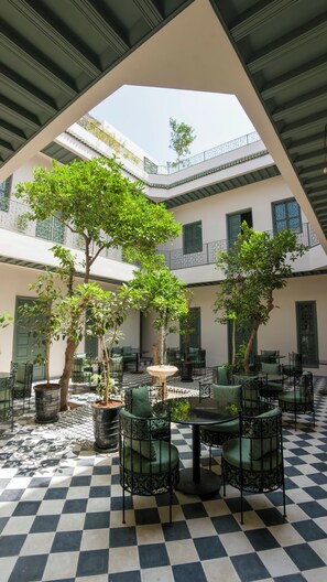 A courtyard with checkered flooring, outdoor seating, and trees. - Riad Mudham (Marrakech)