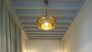 A bedroom with a bed, two hanging lamps, a sofa, and a patterned wall. - Riad Mudham (Marrakech)
