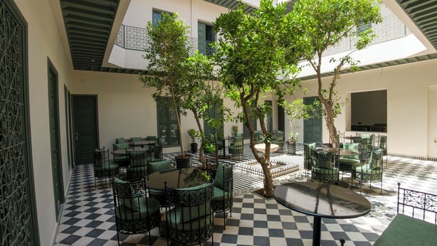 A courtyard with checkered flooring, outdoor seating, and trees. - Riad Mudham (Marrakech)