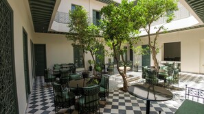 A courtyard with checkered flooring, outdoor seating, and trees. - Riad Mudham (Marrakech)