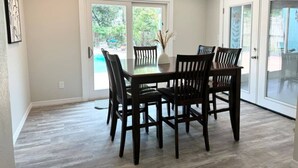 A dining area with a glass table and chairs, a vase with dried plants, and a view of a swimming pool through glass doors. - Pool home in Seminole 5miles to beach (Seminole)