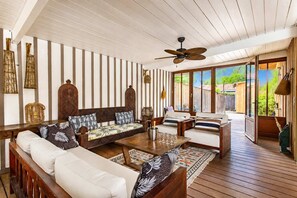 A spacious living area with a wooden ceiling, a ceiling fan, and a large sliding glass door leading to an outdoor patio. - Villa chunga piscine chauffee jacuzzi et clim (Lège-Cap-Ferret)