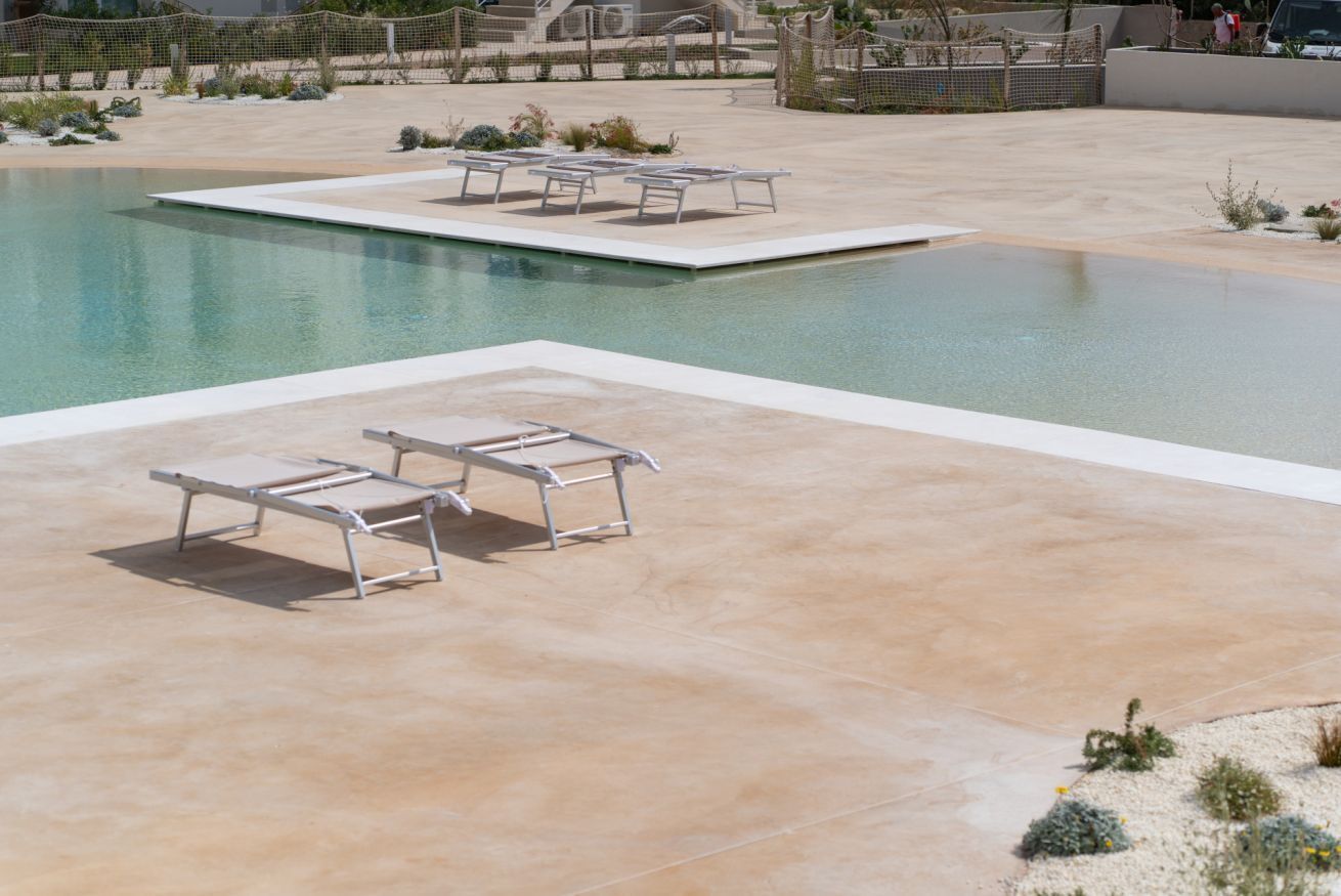 A pool area with lounge chairs and a small pool.