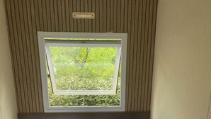 Een kamer met twee bedden, een raam met uitzicht op groen en een plafondlamp.
