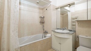 A bathroom with a bathtub, a sink, a toilet, and a mirror. - Bright One Bedroom Apt With Parking and Terrace (Cannes)