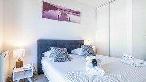 A hotel room with a bed, a nightstand, a lamp, a welcome sign, and a towel on the bed. - Bright One Bedroom Apt With Parking and Terrace (Cannes)