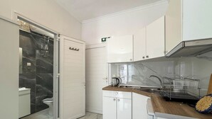 Une cuisine moderne avec des meubles blancs, un pare-feu en marbre et un plan de travail en bois.