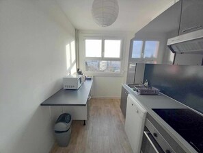 Ett kompakt kök med mikrovågsugn, spis och diskmaskin.