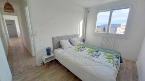 Ein Schlafzimmer mit einem Bett, einem Nachttisch, einem Fenster und einer Tür zu einem anderen Raum.