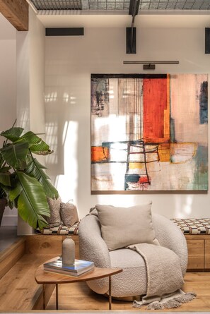 A modern living room with a sofa, a coffee table, a large abstract painting, and a potted plant. - Elgin Corner by onefinestay (London)