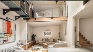 Ein modernes Loft mit Schlafpodest, einer Sitzecke inklusive Sofa und Couchtisch sowie einer Treppe.