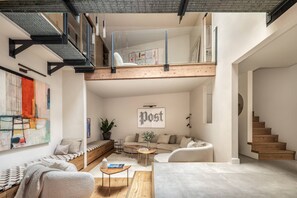 A modern loft with a loft bed, a seating area with a sofa and coffee table, and a staircase. - Elgin Corner by onefinestay (London)