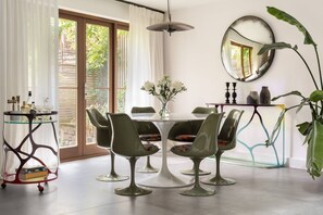 A dining area with a round table, four chairs, a vase with flowers, a hanging light fixture, and a large mirror on the wall. - Elgin Corner by onefinestay (London)