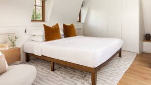 Ein Schlafzimmer mit Bett, Holz-Kopfteil, weißer Bettwäsche und einem flauschigen Teppich.