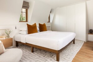 A bedroom with a bed, wooden headboard, white bedding, and a fluffy rug. - Elgin Corner by onefinestay (London)