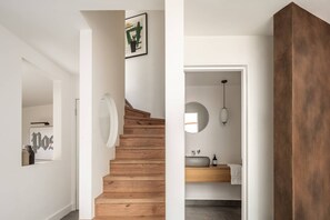 A staircase leading to a bathroom with a round mirror, a sink, and a pendant light. - Elgin Corner by onefinestay (London)