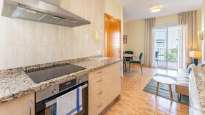 A modern kitchen with a built-in oven, a stainless steel range hood, and a granite countertop. - Los Boliches Rooftop Retreat • 1BR Sleeps 3 - Pass the Keys (Fuengirola)
