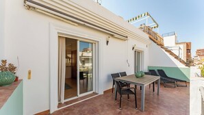 A patio with a table and chairs, a sliding glass door, and a view of the cityscape. - Los Boliches Rooftop Retreat • 1BR Sleeps 3 - Pass the Keys (Fuengirola)