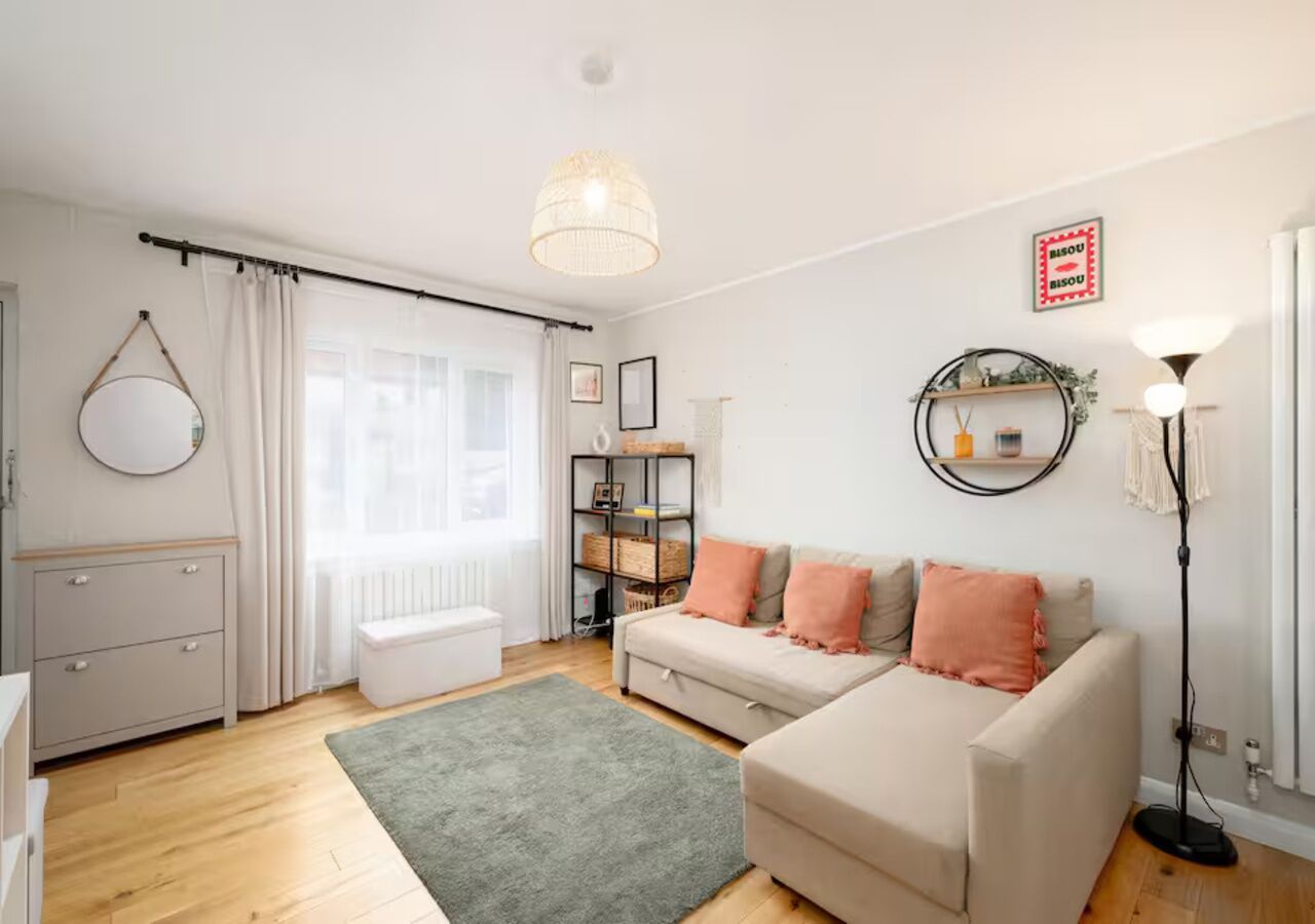 Ein modernes Wohnzimmer mit einer Couch, einem kleinen Tisch, einer Stehlampe und einem Bücherregal.